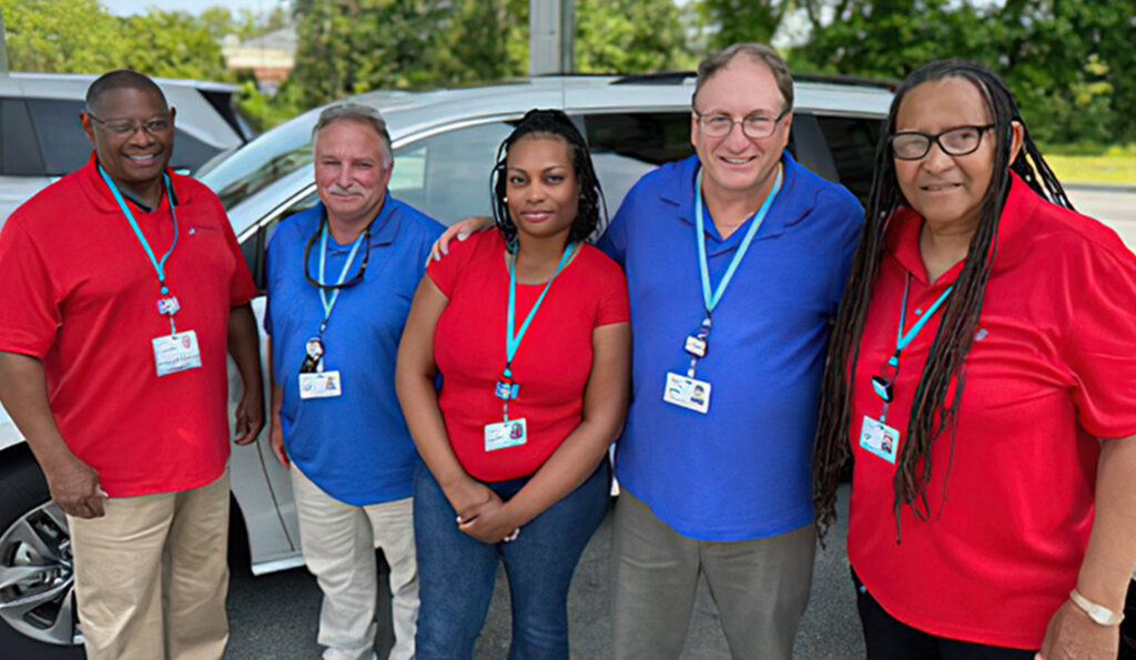 a group of people standing next to each other in front of a car