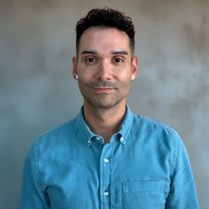 a man in a blue shirt standing in front of a wall