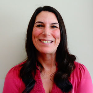 a woman in a pink shirt smiling at the camera