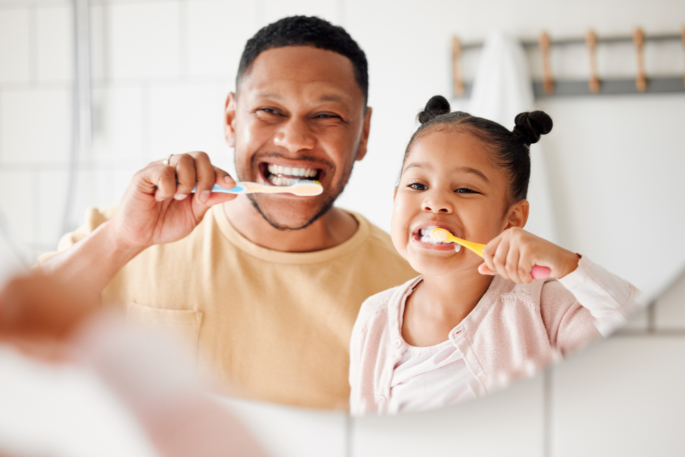 a man and a little girl brushing their teeth