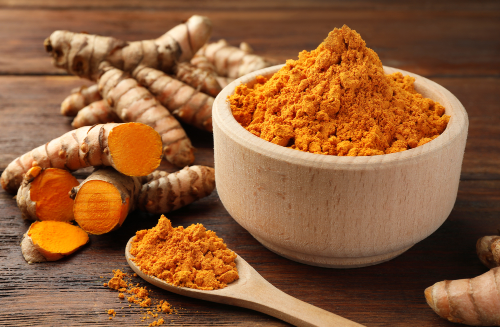 a wooden bowl filled with turmeric and ginger