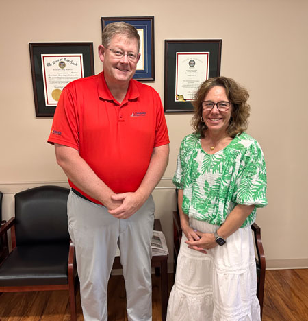 Brian Holland, CEO is in a red shirt and stands beside Dr. Sara Haverty, who is wearing a green floral blouse.